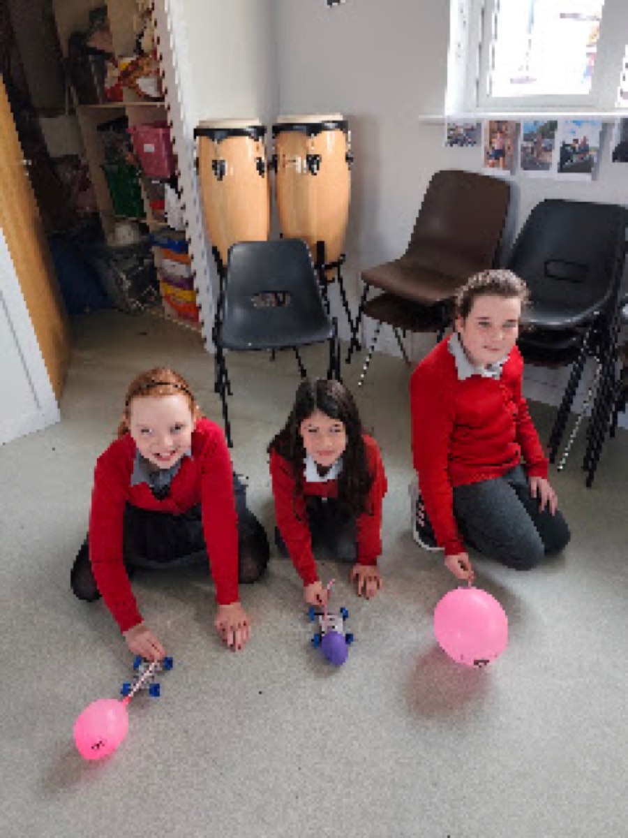Pupils testing the balloon cars they built in the halla